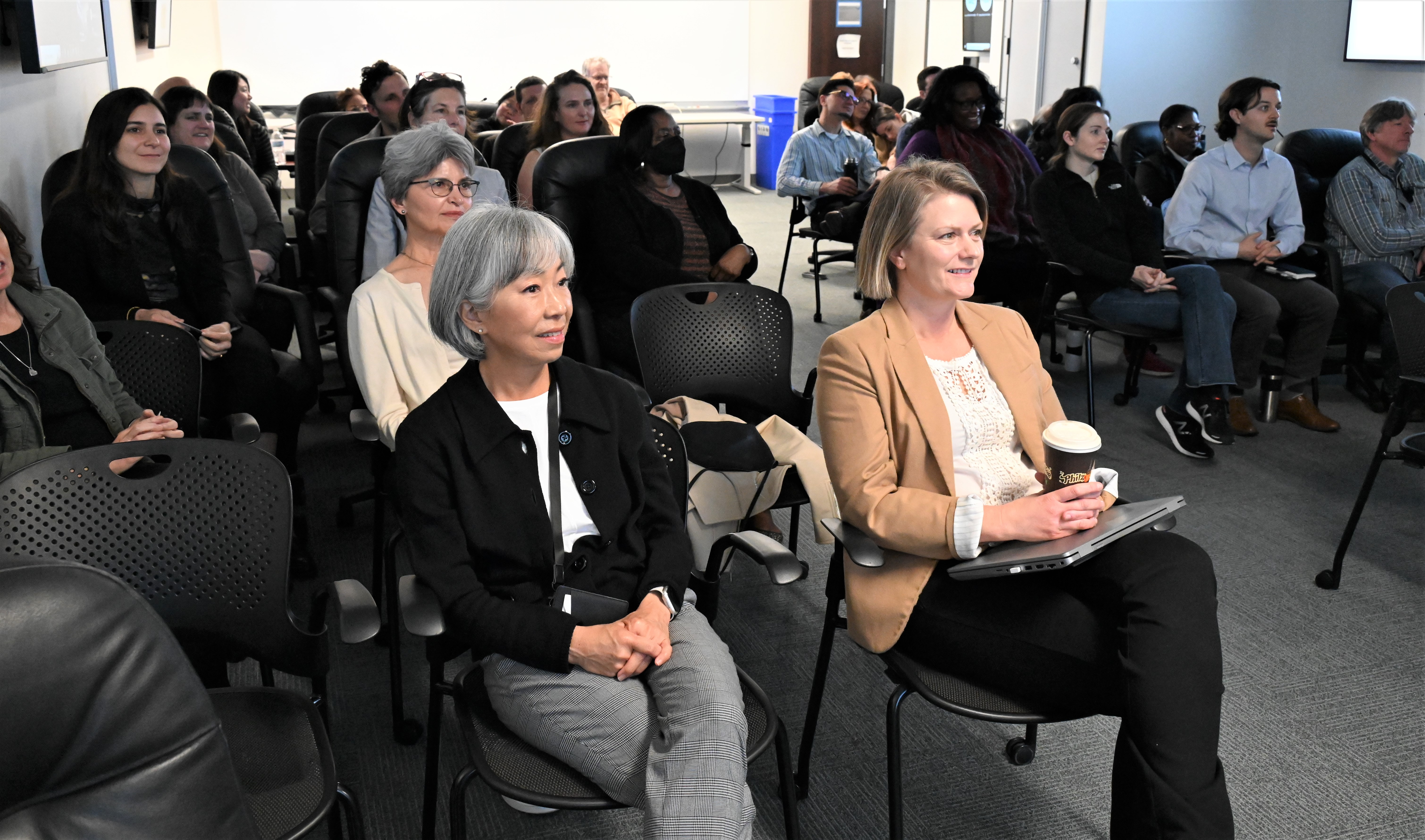 about 30 men and women sitting in a conference room.